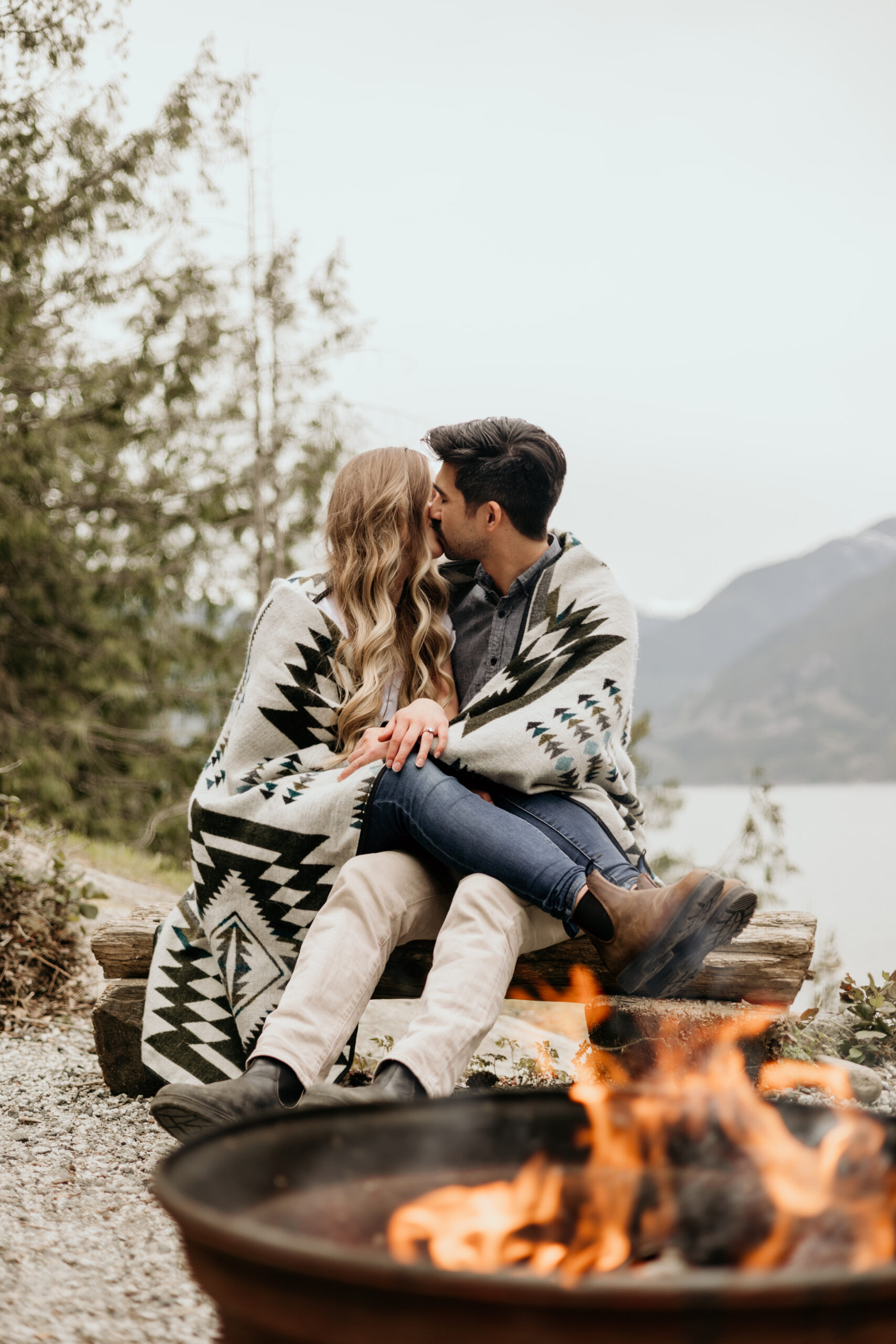 A couple cuddles by the campfire during their engagement session at a campground near Vancouver, BC